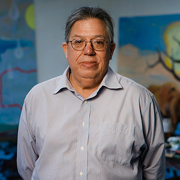 Norman Akers standing in front of two of his paintings