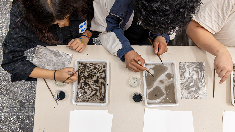 overhead photo of three artists working with ink and brushes