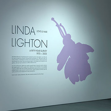 a view of the Nerman Museum gallery hosting the Linda Lighton Exhibition. Exhibition signs is in the foreground and sculptures are visible through the doorway.