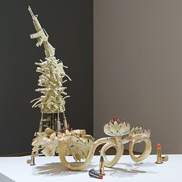 sculptures by Linda Lighton mixing the hard shapes of guns and ammunition with organic, plant-like shapes