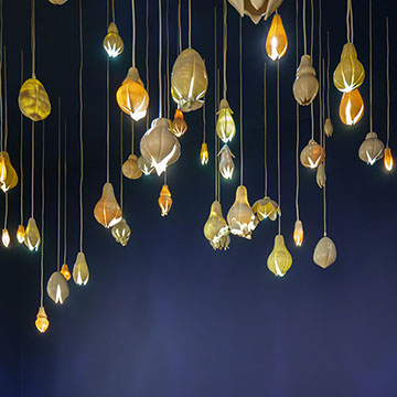 a museum patron looking up at an installation of ceramic lights hanging from the ceiling of the Nerman Museum.