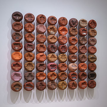 three works of art on display at the Nerman Museum. One is an 8 by 8 display of deflated basketballs; another is a beaded punching bag, and the other is an abstract work.