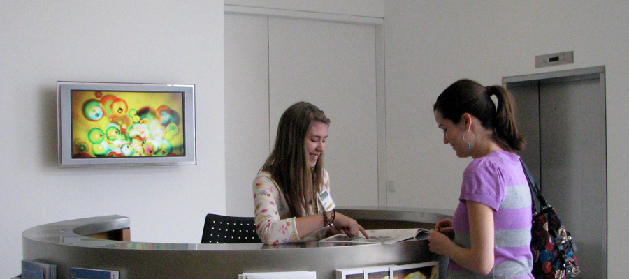 A museum volunteer helps a visitor at the front desk